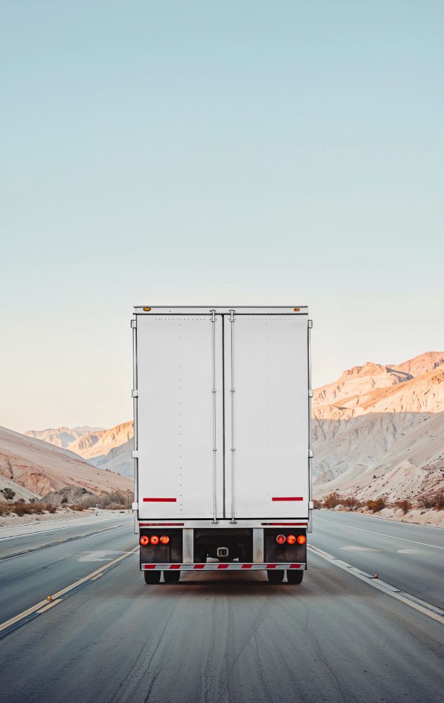 A freight trailer on an open highway running between mountains